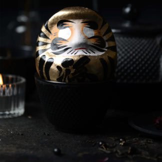 Goldener Daruma vor gusseiserner Teekanne und Kerze; Symbol für Erfolg & Fülle, handbemalt, 9 cm