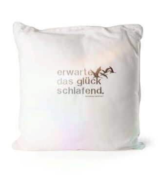 Weißes Kissen mit gesticktem Spruch „erwarte das glück schlafend.“