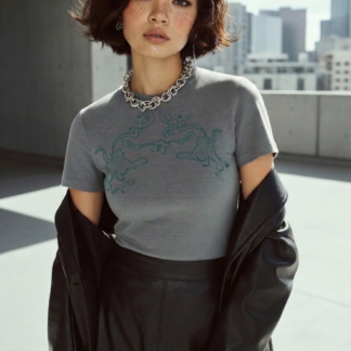 Model trägt graues T-Shirt mit Motiv und schwarzen Blazer in urbaner Outdoor-Szene