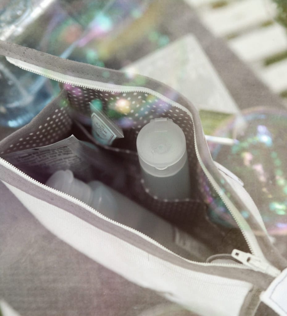 Blick von oben in weißes Beautycase mit dunkelgrauem, weiß gepunktetem Innenstoff und Seitenfächern