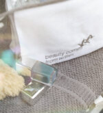 Nahaufnahme des gestickten Schriftzugs „beauty comes from within.“ auf weißem Beautycase