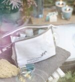Weißes Beautycase mit grauen Paspeln in stimmungsvollem Outdoor-Arrangement mit Pflegeprodukten und Seifenblasen