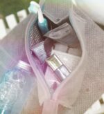 Blick von oben in graues Beautycase mit petrolfarbenem Reißverschluss und dunkelgrauem, weiß gepunktetem Innenstoff
