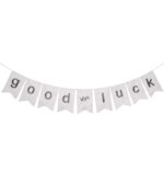 Weiße Stoffgirlande mit grauen Buchstaben „good luck“ auf hellem Hintergrund