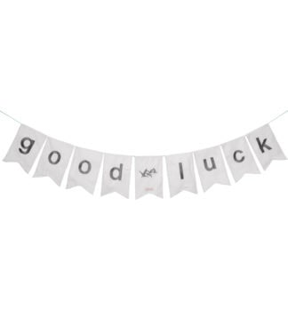 Weiße Stoffgirlande mit grauen Buchstaben „good luck“ auf hellem Hintergrund