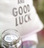 Detailansicht des Kissens „Keep Calm and Good Luck“ mit Glas im Vordergrund