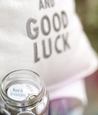 Detailansicht des Kissens „Keep Calm and Good Luck“ mit Glas im Vordergrund