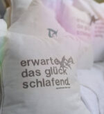 Weißes kleines Kissen mit gesticktem Spruch in ruhiger Outdoor-Szene