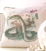 Kissen „Snake“ mit Schlangenmotiv in ruhiger Indoor-Szene mit Kerzen