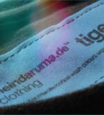 Makroaufnahme des eingenähten Labels im Nacken des braunen Tiger-Shirts