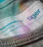 Makroaufnahme des eingenähten Labels im Nacken des grauen Tiger-Shirts