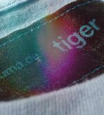 Makroaufnahme des eingenähten Labels im Nacken des hellblauen Tiger-Shirts