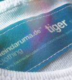 Makroaufnahme des eingenähten Labels im Nacken des weißen Tiger-Shirts
