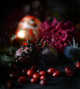 Roter Daruma zwischen dunklen Blumen, Beeren und Feigen; Symbol für Mut und Neustart, handbemalt, 9 cm