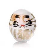 Weißer Daruma mit goldenen Details auf hellem Hintergrund