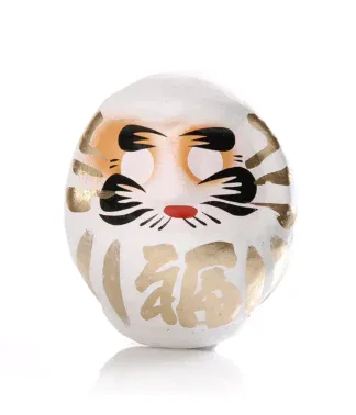 Weißer Daruma mit goldenen Details auf hellem Hintergrund
