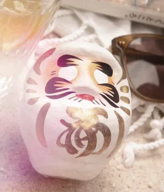 Weißer Daruma auf Sand am Strand, Symbol für Klarheit und Fokus, 9 cm
