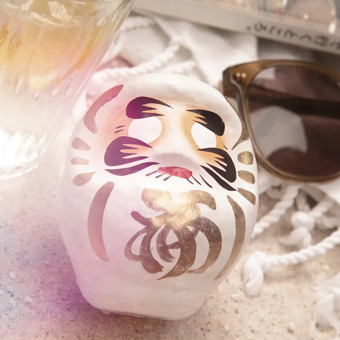 Weißer Daruma auf Sand am Strand, Symbol für Klarheit und Fokus, 9 cm
