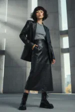 Model trägt graues Damen-T-Shirt mit Motiv, schwarzen Blazer und langen Lederrock in urbaner Umgebung