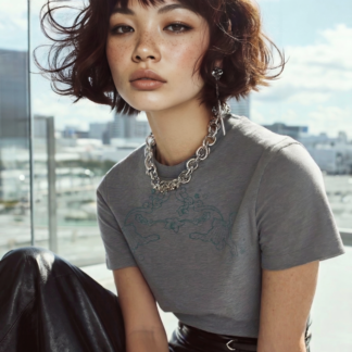 Model trägt graues T-Shirt mit Motiv vor heller Fensterfront und urbanem Ausblick