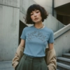 Model trägt hellblaues T-Shirt mit Tiger-Motiv vor urbaner Betonkulisse