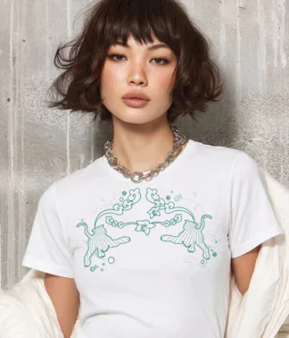 Model trägt weißes T-Shirt mit Tiger-Motiv vor heller Betonwand in urbaner Umgebung