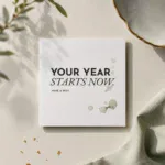 Quadratische Geburtstagskarte „YOUR YEAR STARTS NOW“ auf hellem Untergrund mit dezenten Aquarellflecken.