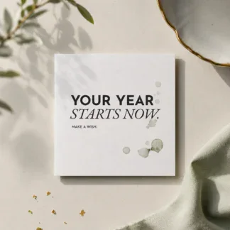 Quadratische Geburtstagskarte „YOUR YEAR STARTS NOW“ auf hellem Untergrund mit dezenten Aquarellflecken.